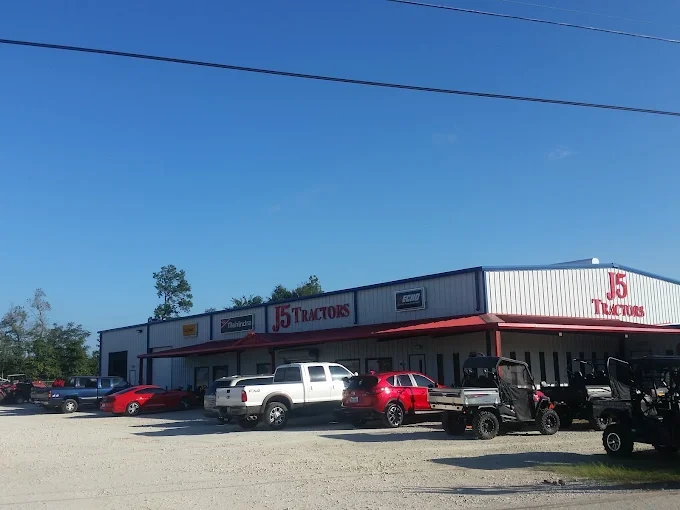 The J5 Tractors storefront in Conroe, Texas, with utility vehicles and trucks parked on the lot below the Mahindra sign